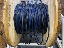 In a busy workshop, a weathered wooden barrel showcases a spool wrapped in black and blue wires, surrounded by tools and ongoing projects that reflect creativity and skill photo