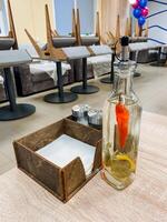 On a beautifully set table in a cozy restaurant, there is a bottle containing a vibrant pepper, adding a touch of color and flavor to the dining experience offered to guests photo