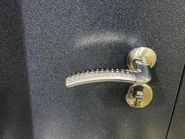 The image showcases a closeup of a modern black door handle, emphasizing its unique design, texture, and intricate hardware details, creating a visually striking appearance photo
