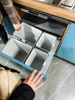 A person is diligently and carefully reaching into a wellorganized drawer that contains three distinct bins, likely searching for an urgently needed item that they require at this moment photo