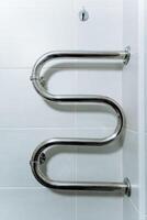 A sleek and modern stainless steel towel rack elegantly hangs on a pristine white tiled wall, effectively adding both functionality and a touch of style to any bathroom or laundry space photo