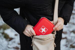 A person is meticulously organizing and fitting a first aid kit into their purse so that it is easily accessible at a moments notice during any unexpected emergencies or situations photo