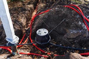 A bunch of tangled wires are laying in the dirt next to a tall pole photo