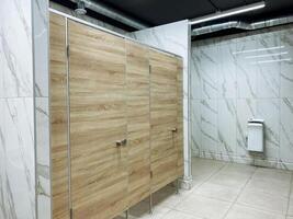 A public restroom featuring elegantly designed wooden stalls complemented by luxurious marble walls, creating an inviting atmosphere for users. The overall design reflects modern aesthetics photo