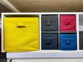 On a wellorganized shelf, there lies a bright yellow box positioned right in the center, standing out against the background, making it quite the eyecatching sight among other items photo