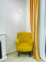 In a cozy corner of a welldecorated room, there is a bright yellow chair that is resting peacefully next to a charming fireplace, adding a delightful pop of color and comfort to the space photo