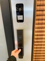 An individual is pressing down on a button located on an electronic door lock, which is designed to manage secure access by allowing or denying entry at critical points within a building photo