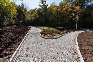 A beautifully curved pathway is currently under construction, framed by lush trees and vibrant nature all around, enhancing the scenery photo