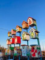 A vibrant assortment of colorful birdhouses is creatively stacked one upon another, creating an engaging and whimsical visual display that captivates the viewers attention photo