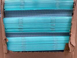 There is a stack of blue straws neatly arranged within a cardboard box, showcasing a vibrant azure color that stands out beautifully against the neutral material of the container photo