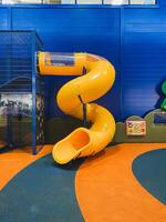 In a vibrant playground setting, there is a bright yellow spiral slide that stands out, complemented by an eyecatching blue wall positioned just behind it, creating a lively atmosphere photo