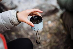 An image of a backpacker peacefully enjoying a hot drink in a camping mug in nature represents serenity and comfort in the wilderness, a tranquil escape into nature photo