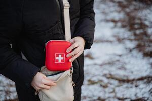A person is confidently holding a first aid kit in their hand while standing in a location that may require medical assistance or emergency supplies, demonstrating preparedness photo