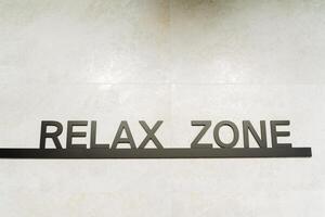 Rectangular relax zone sign with artistic font and graphics on a wall, possibly related to a brand or automotive theme. Keywords Rectangle, Font, Art, Brand, Automotive photo