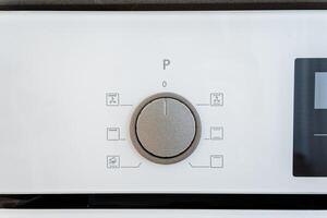 The white kitchen appliance control panel features userfriendly rotary dial settings for convenient cookware use, adding minimalist aesthetics and programmable options photo