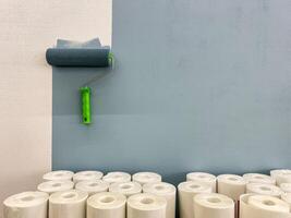 A freshly painted wall showcases a clean finish, with a paint roller placed nearby and paper towels in the background, highlighting tools used in this crafting process photo
