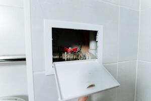 A person is currently engaged in the process of carefully opening a valve that is situated in a bathroom, most likely for the purpose of managing the flow of water or other utilities photo
