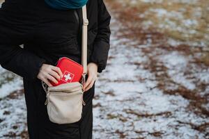 A woman is carrying an essential first aid kit conveniently placed in her purse, which she might need for any unexpected situations that arise while she is out and about photo