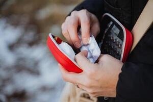 A person is carefully taking a small pill out of a bright red case that is designed for holding medication and vitamins while ensuring to use their fingers and thumb appropriately photo