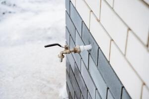 A faucet is securely attached to the side of a sturdy brick building, which serves as an essential household hardware component for various plumbing needs in everyday life photo