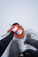 In a winter wonderland, a person is seated in the soft, cold snow while gripping a first aid kit tightly in their hands, ready for any adventure or emergency that may arise photo