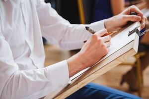 Man using pencil to draw gesture on paper during formal event photo