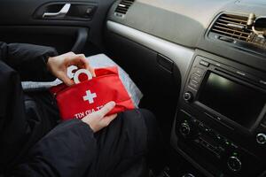 In a vehicle, a person is seated inside a car while holding a wellequipped first aid kit, ready to assist in case of any emergencies that might arise during their journey photo