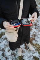 A woman can be observed holding a small case that contains various pills within it, suggesting that she might be prepared for a travel journey or a recreational activity ahead photo
