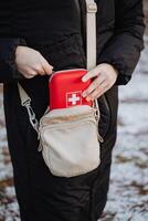 A woman is securely carrying a first aid kit inside her purse, ensuring that she is wellprepared for any potential emergencies that may arise during her daytoday activities photo