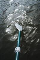 Close up of a paddle slicing through the liquid surface of a lake photo
