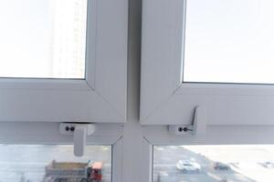 Here is a detailed closeup view of a white plastic window that features a handle, showcasing its design and functionality for residential buildings. It is an essential fixture in any house photo