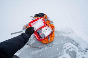 In a snowy landscape, an individual holds a vital first aid kit, essential for handling injuries or emergencies in winter, ensuring safety and preparedness in harsh conditions photo
