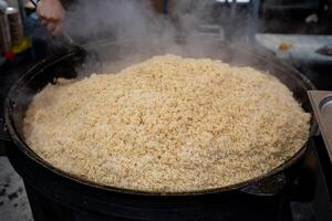 A sizable pot brimming with rice is currently being cooked on a stove, creating a delicious and wholesome dish that serves as a staple food in many cuisines around the world photo