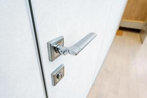 A closeup view of a door handle on a white door highlights the intricate design and features. The image showcases the beauty of the wood and the craftsmanship of the handle photo