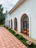 A stunning white building with elegant arched windows is complemented by a charming brick walkway leading to its grand entrance, captivating all who pass by and leaving a lasting impression photo