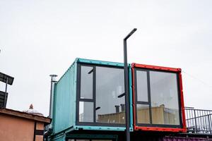 A unique architectural structure designed using shipping containers, characterized by an abundance of large windows that allow natural light to illuminate the interior space photo