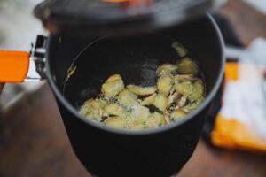 Pieces of ginger are boiled in boiling water in a saucepan, the lid of the cauldron is ajar, making a hot drink, ginger warming tea. photo