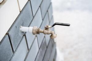 This is a detailed closeup image featuring a faucet that is mounted on a rugged brick wall, showcasing the intricate design and details of both the plumbing fixture and the brickwork photo