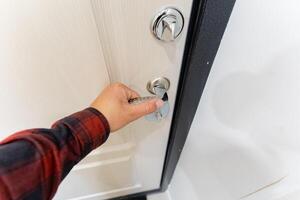 A person is using a key to open the door, demonstrating a common action that is necessary for gaining entry into a space, highlighting the significance of keys in daily life photo