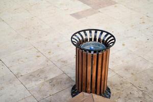 A wooden trash can is currently placed on a beautifully designed tiled floor, adding a rustic touch to the overall aesthetics of the space while serving its purpose effectively photo