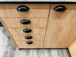 In this visually striking image, one can see a closeup of an exquisitely crafted wooden cabinet featuring stylish black handles that greatly enhance its overall sleek and elegant design photo