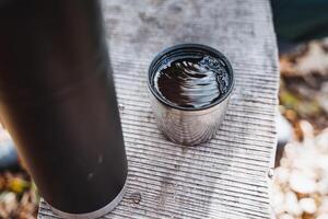 A steaming cup of coffee sits on a crafted wooden table, combined with an aromatic fragrance, creating a warm and cozy atmosphere that encourages relaxation and enjoyment photo