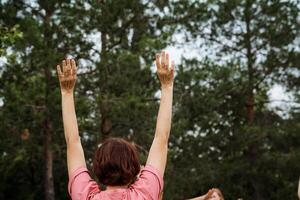 A person is raising hands in the forest during the daytime, displaying a powerful gesture. This scene evokes feelings of freedom, harmony, and connection with nature photo