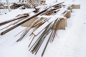 SnowCovered Steel Rebars and Metal Rods are Neatly Stacked on a Construction Site, Ready for Upcoming Projects, Highlighting the Unyielding Nature of Winters Impact on Industry photo