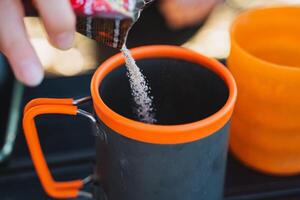 A person carefully pours a generous amount of sugar into a steaming cup of freshly brewed coffee, enhancing its naturally rich flavor and ensuring the perfect enjoyment of the beverage photo