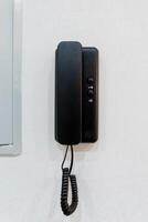 A classic black telephone against a bright white wall creates a striking contrast, enhancing the rooms decor and making it more inviting and visually pleasing to those who enter photo