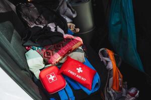 A bright red first aid kit, essential for immediate medical assistance, is neatly placed in the back of a car, ready for unexpected emergencies while traveling or outdoors photo