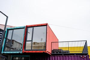 A vibrant and colorful shipping container that features a spacious balcony situated elegantly on its upper portion, adding a unique architectural touch to its design and usage photo