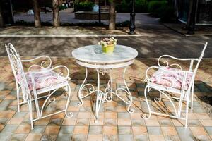 A beautiful wooden table and chairs are placed on a patio, complemented by a vibrant pot of flowers. This outdoor furniture creates a tranquil setting within a landscaped area photo