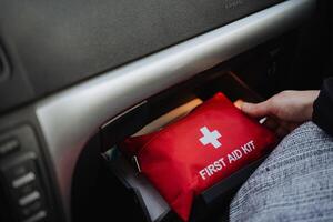 A person can be seen holding a wellequipped first aid kit inside their car, which is important for ensuring safety while on the road and being prepared for any emergencies that might arise photo